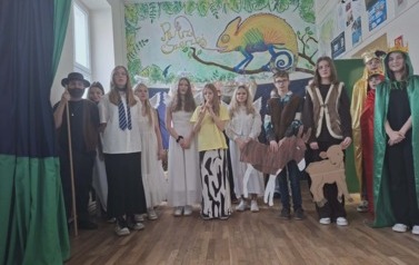 Uczniowie podczas biorący w przedstawieniu jasełkowym stoja w przebraniach na środku i spiewają kolędę