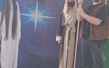 Uczniowie podczas przedsatwienia jasełek: W przebraniach Maryja z lewej strony, w środku J&oacute;zef, z prawej pasterz stoją na tle gwieździstego nieba