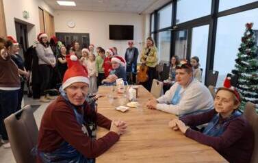 Grupa dzieci i senior&oacute;w siedząca przy stole podczas spotkania świątecznego