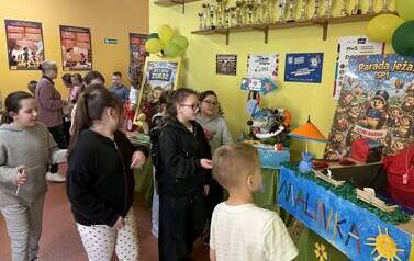 Grupa uczni&oacute;w na szkolnym korytarzu oglądajaca prace konursowe przygotowane na paradę jeża