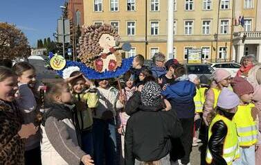 Duża grupa dzieci z papierowymi z elementami przebrania za jeża. W tle baner z hasłem Jeż i jego Zgierz
