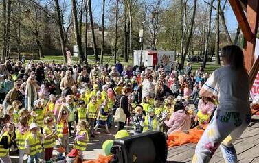 Duża grupa dzieci w Parku Miejskim podczas imprezy Parada jeża ze Zgierza. Na scenie tańczy instruktorka zumby zachęcając dzieci do zabawy