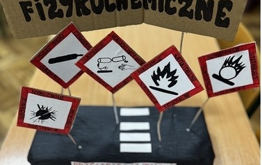 Model z piktogramami ustawionymi na steropianowej czarnej podstawie z napisem bezpieczeństwo fizyko-chemiczne
