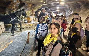 Duża grupa uczni&oacute;w w podziemiach w kopalni soli w Wieliczce w tunelu obrazujących wydobywanie soli, w tym z pomocą koni