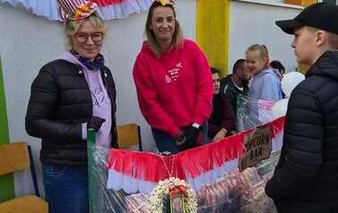 Grupa os&oacute;b na boisku szkolnym w czasie pikniku rodzinnego przy stoisku z grami