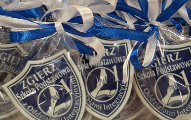 3 Tarcze szkolne z nazwą i logo szkoły zapakowane w przezroczysta folię i przewiązane biało- niebieskim wstążkami