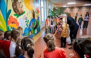 Grupa dzieci podczas przedstawienia "Gdzie jest jest jeż?" na tle dekoracji z kolorowych jesiennych liści, dyni i owoc&oacute;w jesieni