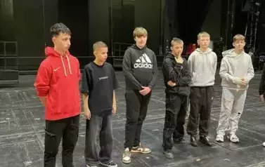 Grupa uczni&oacute;w stojąca na scenie Teatru Wielkiego w Łodzi.