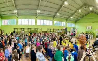 Duża grupa dzieci i opiekun&oacute;w tańcząca w sali gimnastycznę podczas zakończenia imprezy Parada jeża ze Zgierza.