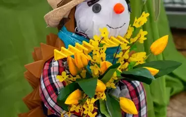 Jeż ogrodnik w kapeluszu i trzymający kosz kwiat&oacute;w w łapkach