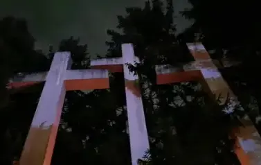 Trzy duże krzyże w barwach biało-czerwonych stojące w Palmirach przy cmentarzu