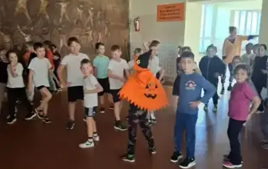Duża uczni&oacute; na szkolnym korytarzu, w przebraniach halloweenowch podczas roztańczonej przerwy