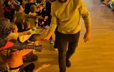 Duża grupa dzieci w przebraniach za postacie z bajek tańczy w sali gimnastycznej.