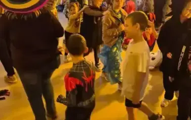 Duża grupa dzieci w przebraniach za postacie z bajek tańczy w sali gimnastycznej.