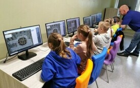 Uczniowie siędzący przy stolikach przed laptopami