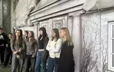 Grupa uczni&oacute;w stojąca na scenie teatralnej na tle dworku. Na dachu dworku śnieg.