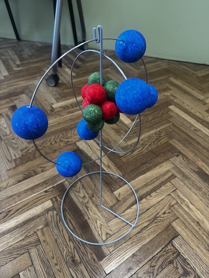 Model atomu z&nbsp;kolorowych kulek na&nbsp;metalowym stojaku
