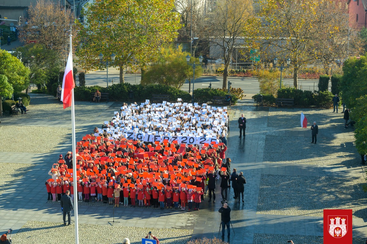 Duża grupa uczni&oacute;w tworzy na&nbsp;placu przed Urzędem Miasta Zgierza żywą flagę.