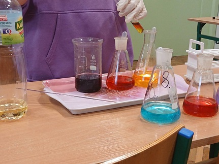 St&oacute;ł laboratoryjny na&nbsp;kt&oacute;rym stoją kolby stożkowe z&nbsp;kolorowymi cieczami o&nbsp;r&oacute;żnej gęstości