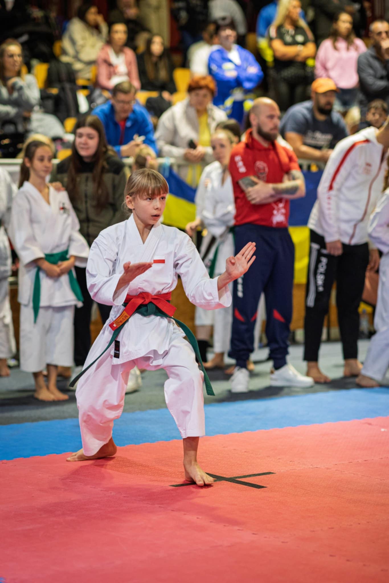 Dziewczynka w&nbsp;stroju karateki na&nbsp;macie podczas walki w&nbsp;hali sportowej w&nbsp;Słowenii