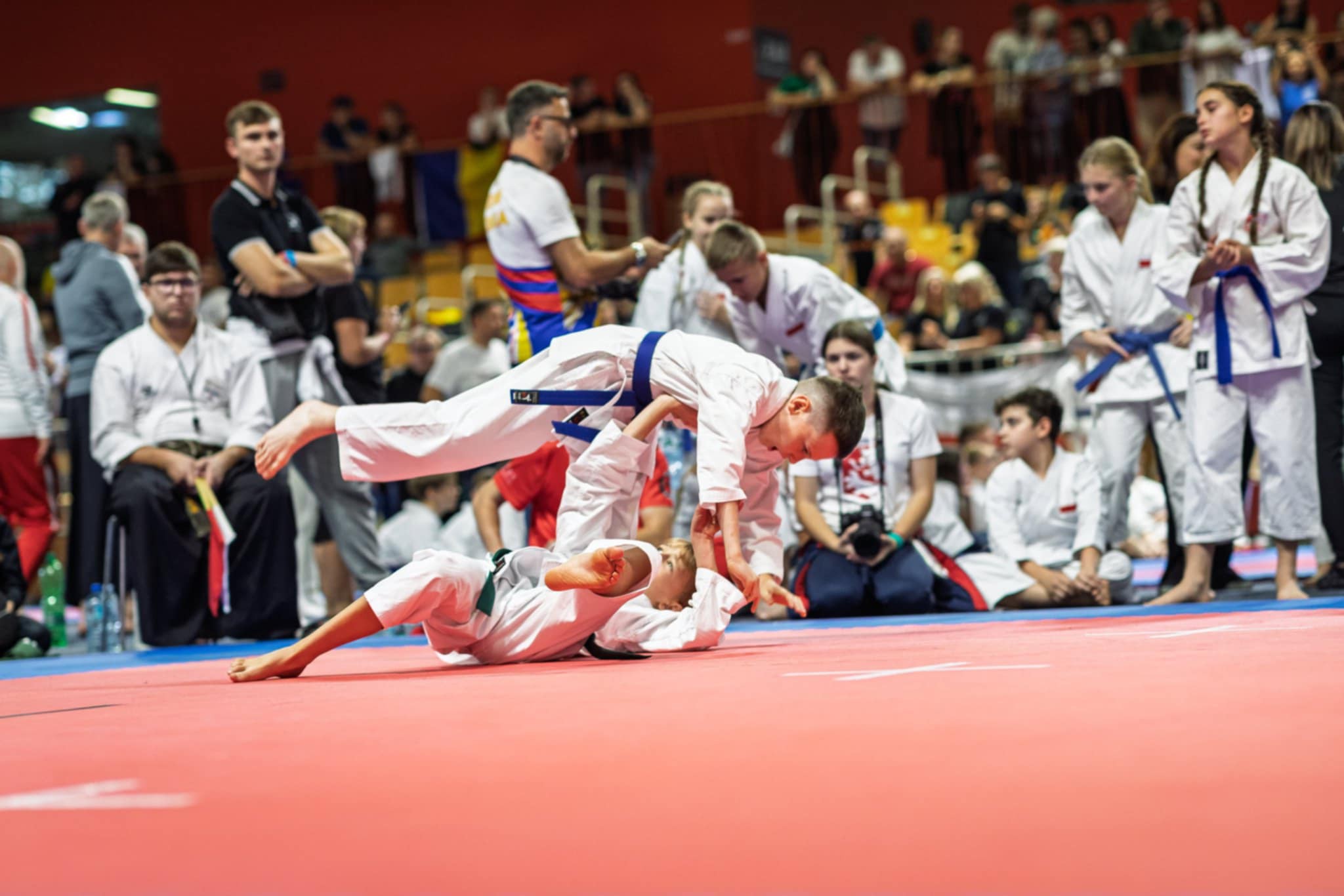 Dw&oacute;ch zawodnik&oacute;w - chłopc&oacute;w w&nbsp;czasie walki na&nbsp;zawodach karate, na&nbsp;macie w&nbsp;hali sportowej