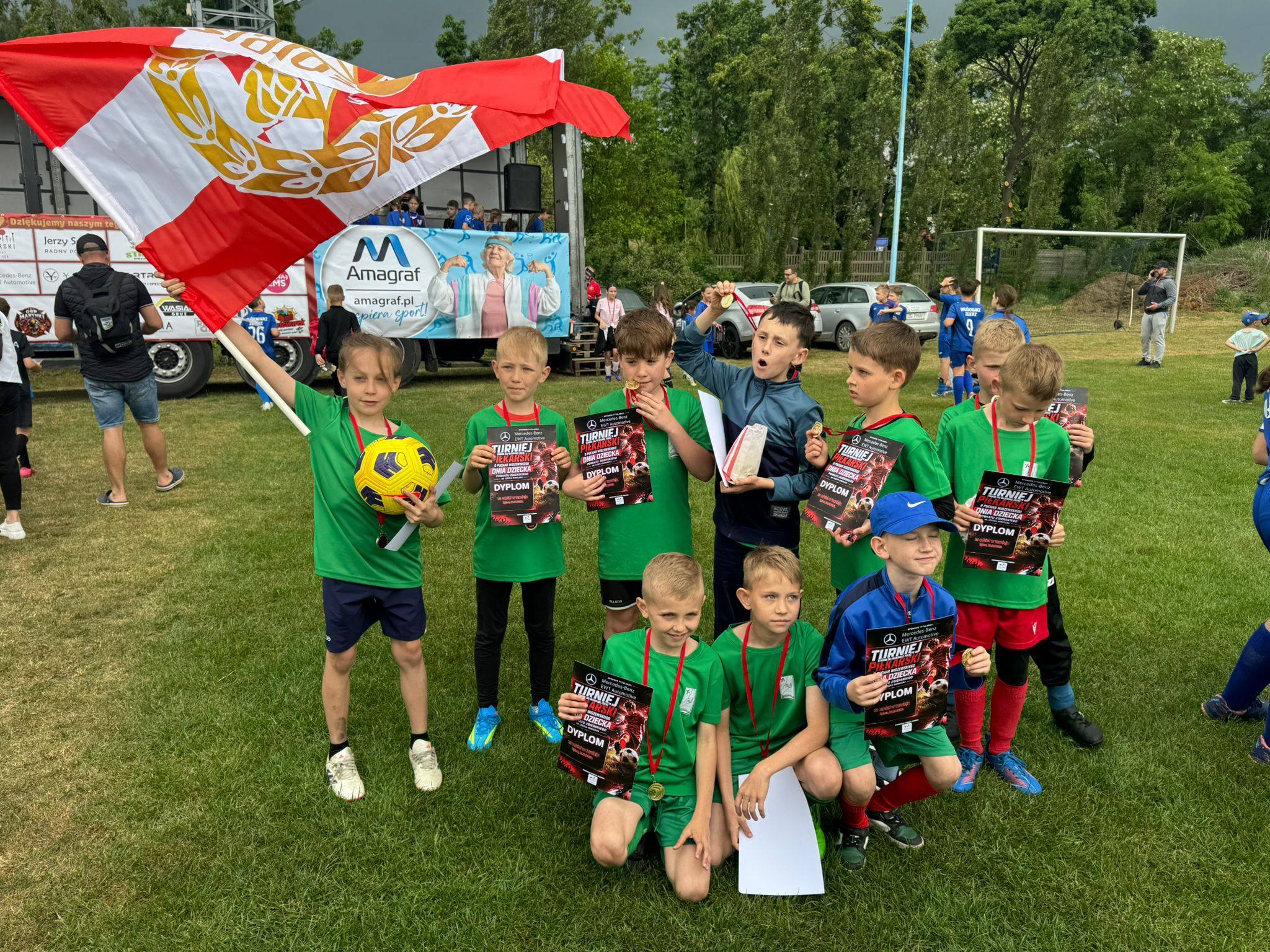 Grupa dzieci w&nbsp;zielonych piłkarskich strojach na&nbsp;murawie stadionu