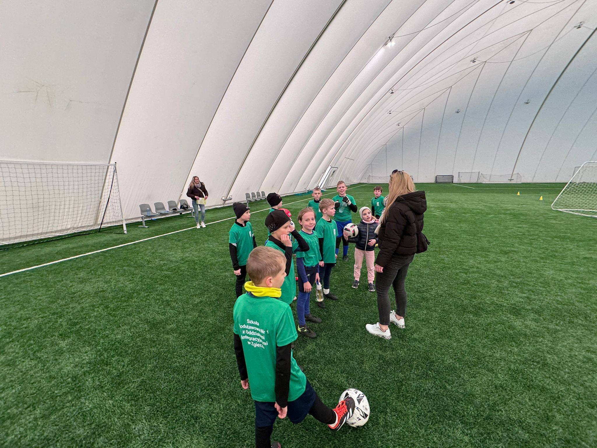 Grupa dzieci na&nbsp;boisku sportowym podczas gry w&nbsp;piłkę nożną