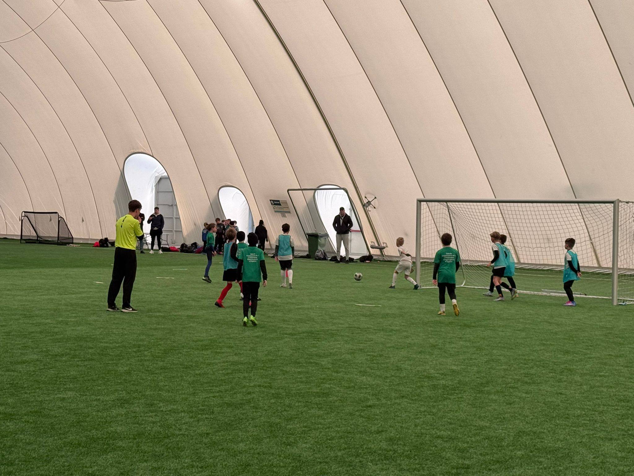 Grupa dzieci na&nbsp;boisku sportowym podczas gry w&nbsp;piłkę nożną