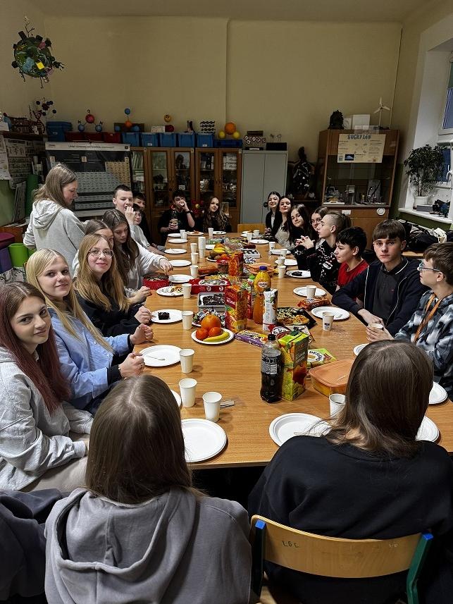 Grupa uczni&oacute;w przy nakrytym stole podczas wigili koła chemicznego