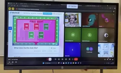Ekran monitora interaktywnego z wyświetloną grą online i okienkami uczestników spotkania