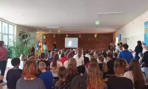 Duża grupa uczniów ogląda na dużym ekranie start w kosmos rakiety z Polakiem na pokładzie