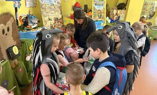 Grupa uczniów na szkolnym korytarzu oglądajaca prace konursowe przygotowane na paradę jeża