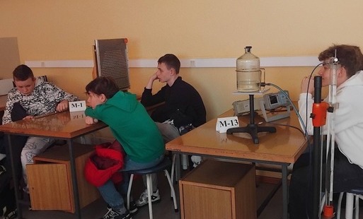Uczniowie siedzą przy stolikach doświadczalnych w pracowni fizyki Uniwersytetu Łodzkiego
