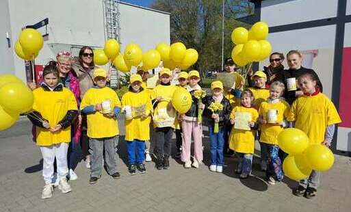 Grupa uczniów z opiekunami w żółtych koszulkach i żółtymi balonami pozują do zdjęcia przed rozpoczęciem zbiórki Pla nadziei