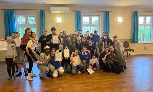 W sali konferencyjnej duża grupa uczniów pozuje do zdjęcia z certyfikatami Euroweek