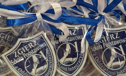 3 Tarcze szkolne z nazwą i logo szkoły zapakowane w przezroczysta folię i przewiązane biało- niebieskim wstążkami
